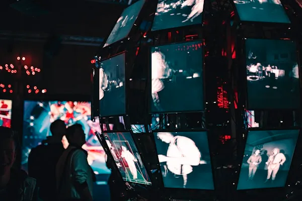 A group of people standing around a display of video screens.