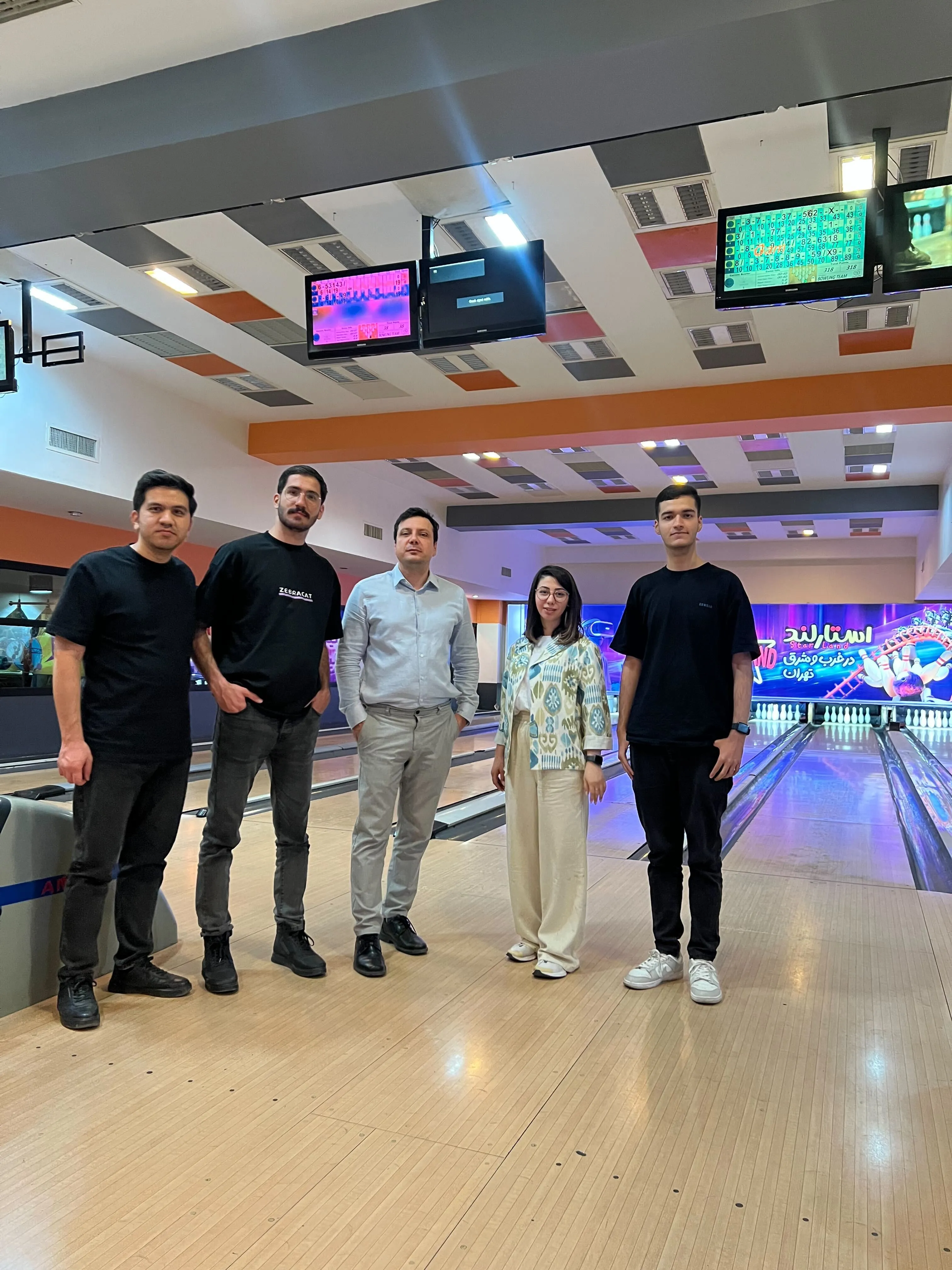 A group of people standing around a bowling alley.